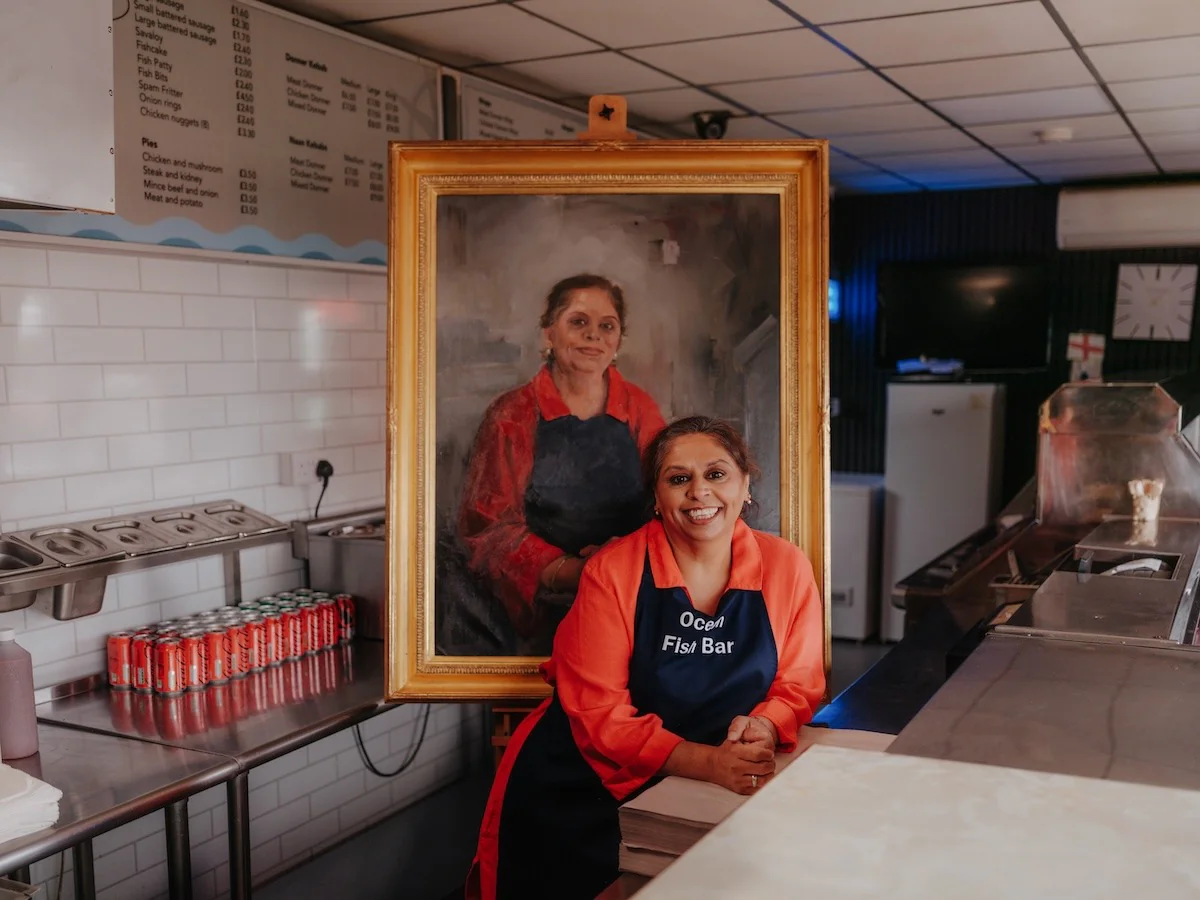 Pindy Kaur ao lado do seu retrato no Ocean Fish Bar, em Barnsley